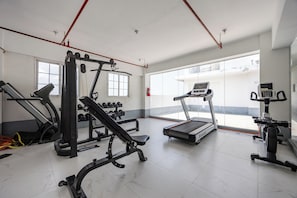 Una palestra con tapis roulant, macchinari per pesi e manubri.