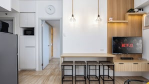 Een moderne keuken met een magnetron, koelkast en houten barstoelen.