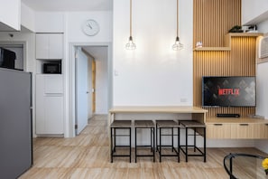 Una cucina moderna con forno a microonde, frigorifero e sgabelli da bar in legno.