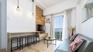 Een moderne woonkamer met een bank, een televisie, een bar en een balkon met uitzicht.
