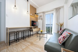 Un soggiorno moderno con divano, televisione, angolo bar e balcone con vista.