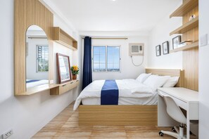 Hotellihuone, jossa on sänky, työpöytä ja ikkuna, josta on näkymä.