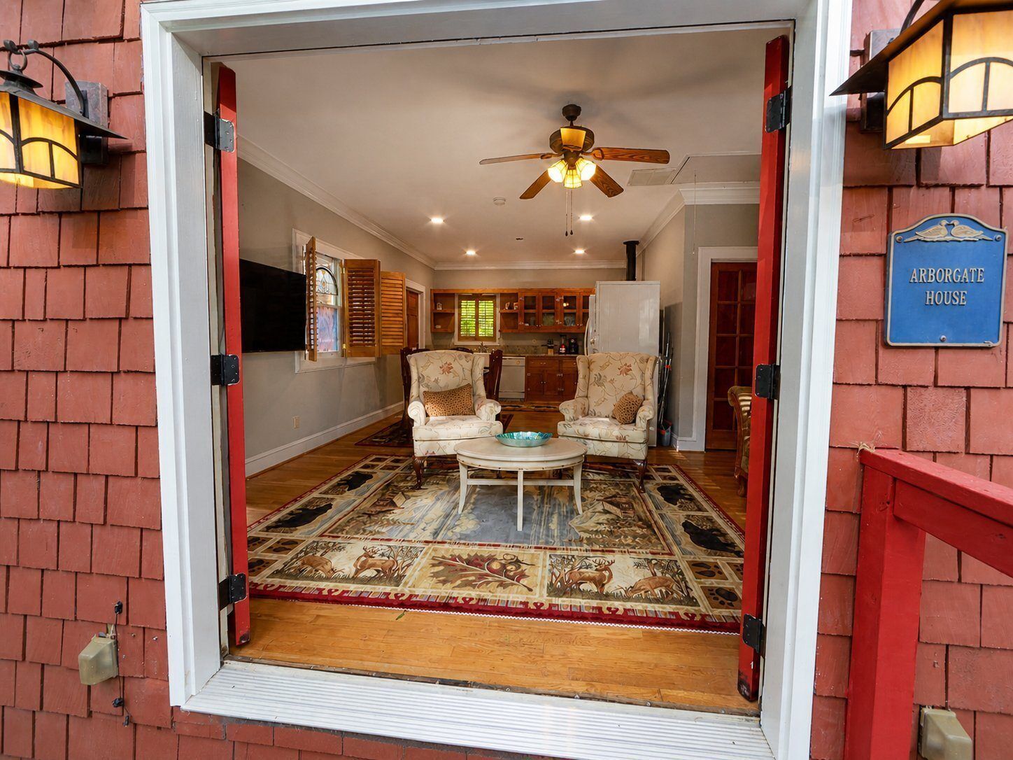 A living room with a ceiling fan, two patterned armchairs, a coffee table, and a rug with animal prints.