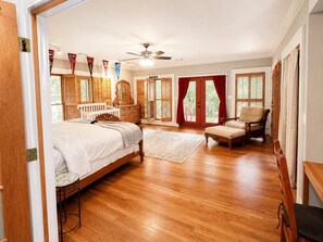 Ein geräumiges Schlafzimmer mit einem großen Bett, einer Holzkommode, einem Sessel und einem Schreibtisch.