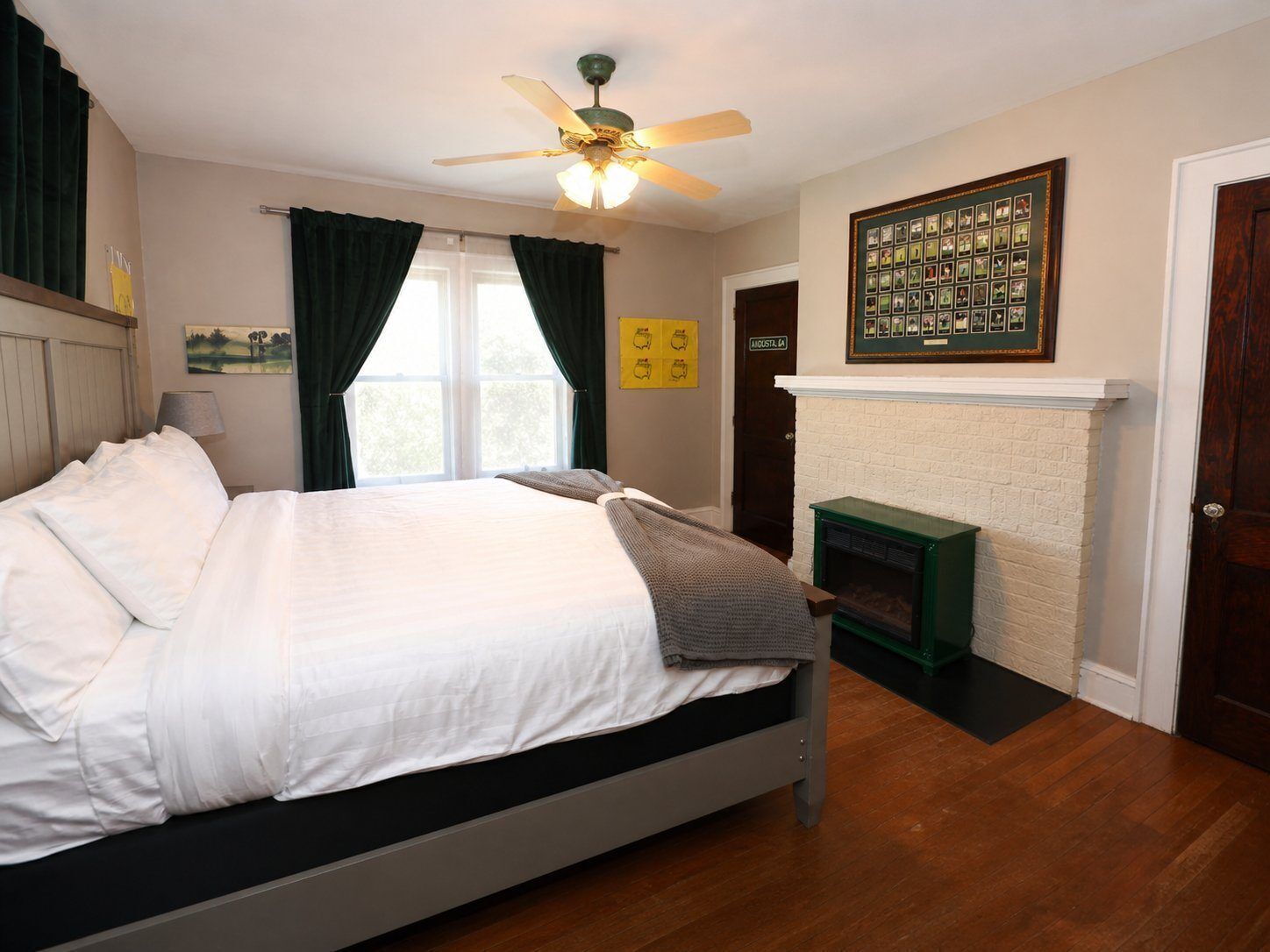 A bedroom with a bed, a ceiling fan, a fireplace, and a door labeled 'AUSTIN.'