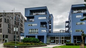 Een modern blauw gebouw met meerdere balkons en grote ramen.