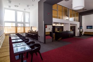 A conference room with glass tables and chairs, a reception desk, and a red carpeted area. - Hotel 99 (Chomutov)
