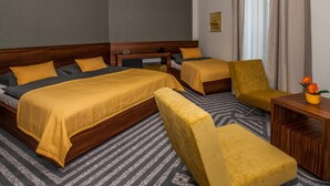 Een hotelkamer met twee bedden, een bank, een kleine tafel en een decoratieve vaas.
