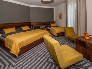 A hotel room with two beds, a sofa, a small table, and a decorative vase. - Hotel 99 (Chomutov)