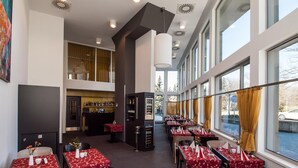 Een restaurant met meerdere tafels, een bar en grote ramen.