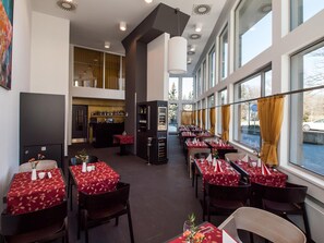 A restaurant with multiple tables, a bar area, and large windows. - Hotel 99 (Chomutov)