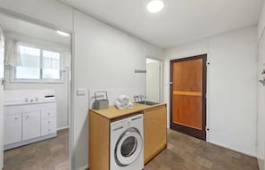 Ein kleines, modernes Badezimmer mit Waschmaschine, Waschbecken und Spiegel.