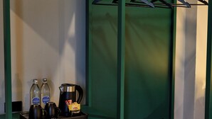 Een groen metalen schap met een waterkoker, twee flessen en een dienblad met Lipton theezakjes.