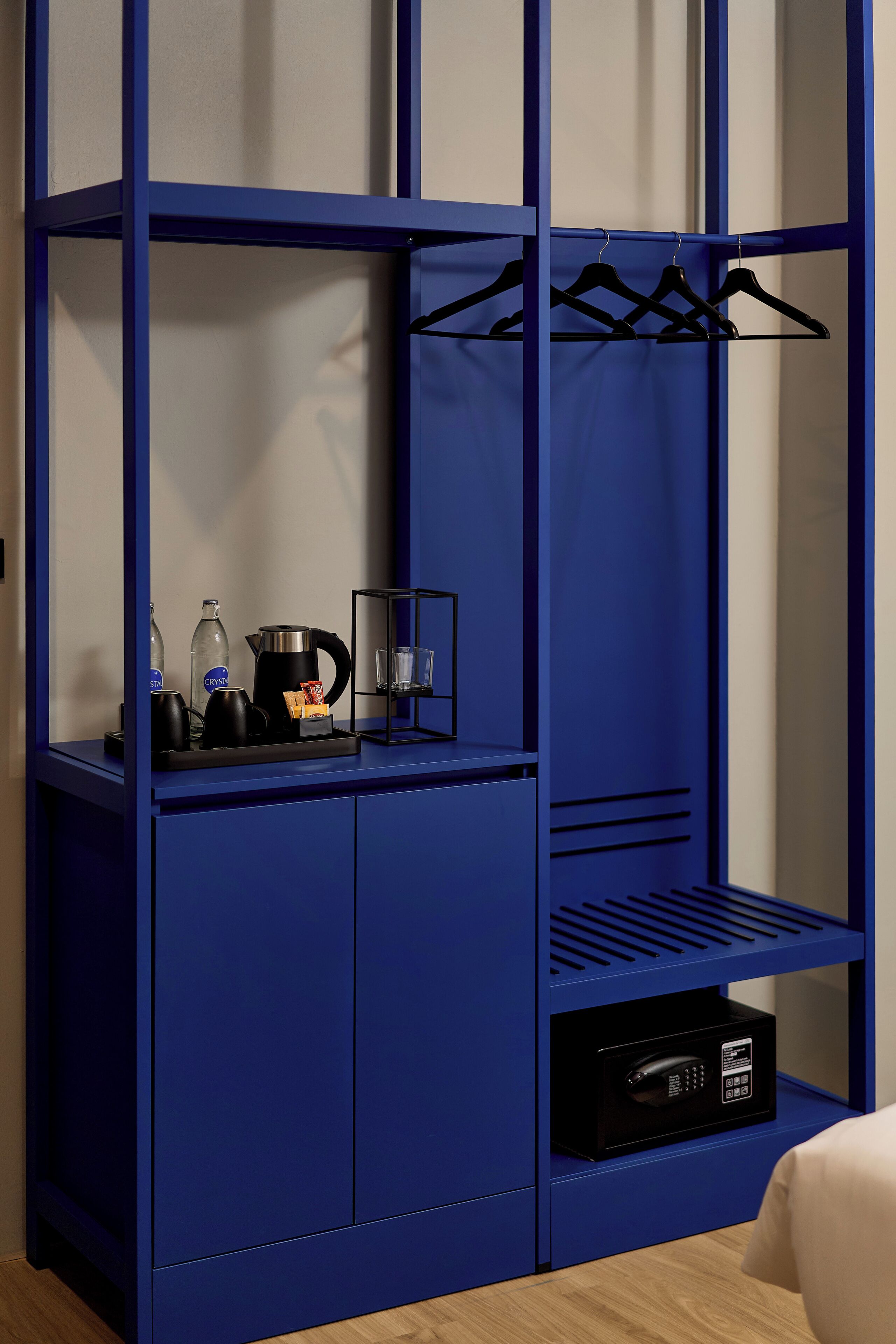 A blue wardrobe with a coffee maker, kettle, and glass on the top shelf.