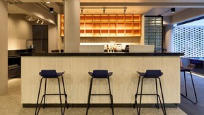Een moderne bar met een centrale toonbank en drie barkrukken.