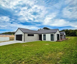 Ein modernes, zweistöckiges Haus mit Garage, großen Fenstern und einem Rasen.