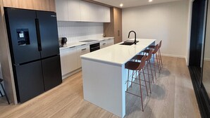 Una cocina moderna con una isla central, taburetes de bar y un refrigerador negro.