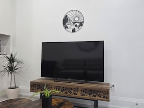 Un téléviseur à écran plat fixé sur un meuble en bois, avec un élément décoratif mural au-dessus.
