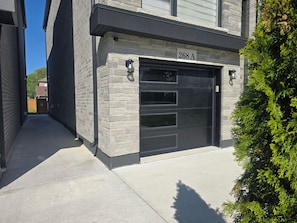 Un bâtiment doté d’une porte de garage, avec un panneau indiquant le numéro « 268 A » au-dessus, et un petit arbre sur la droite.