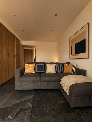 Ein modernes Wohnzimmer mit einem Ecksofa, einem großen gerahmten Kunstwerk und einem Holzschrank.