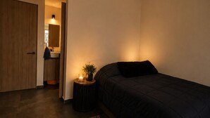 A bedroom with a bed, a bedside table with a candle, a rug, and a door leading to a bathroom. - Roma Habitat. Loft in Roma Norte.
Designed for the modern traveler (Ciudad de México)