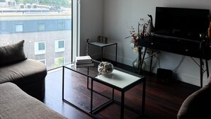 Un soggiorno moderno con un'ampia finestra, una televisione a schermo piatto e un design minimalista.