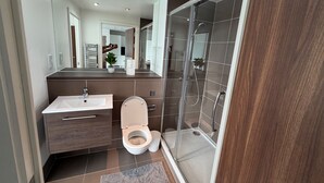 Un bagno moderno con doccia, wc, lavandino e uno specchio grande.