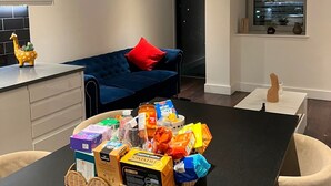 Een moderne woonruimte met een donkerhouten eettafel, een blauwe bank met rode kussens, een keuken en een raam met uitzicht op de stad.
