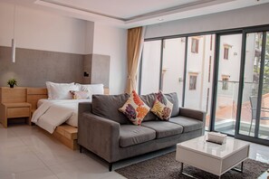 A modern bedroom with a bed, a sofa, a coffee table, and large windows.