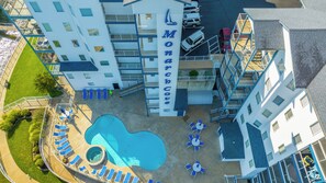 A multi-story hotel with a swimming pool, outdoor seating, and a sign reading 'Monarch Cove'.