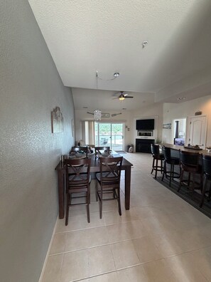 A spacious kitchen with a dining area, a ceiling fan, and a view through the window.