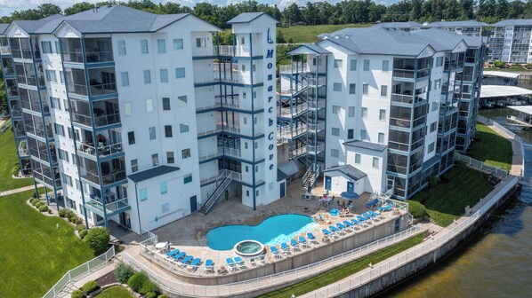 A multi-story hotel with a central courtyard pool, outdoor seating, and a waterfront view.