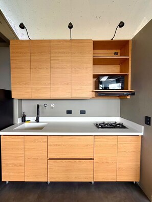 Eine moderne Küche mit Holzausstattung, einer eingebauten Mikrowelle, einem Gasherd und einem Spülbecken.