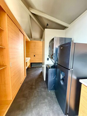 A compact kitchen with a black refrigerator, wooden cabinets, and a microwave. - Vista Hotel Medellin (Medellín)
