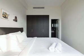 A hotel room with a bed, white linens, a dark wardrobe, and two framed pictures on the wall. - Vibrant Darlinghurst Inner City Oasis (Darlinghurst)