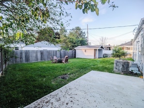 A backyard with a wooden deck, a shed, and a lawn.