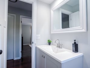 Une salle de bain avec un lavabo blanc, un miroir et un distributeur de savon liquide.