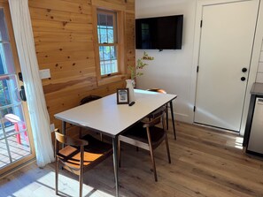 L’intérieur d’une cabane en bois comprend une table à manger, des chaises, un téléviseur fixé au mur et une porte.