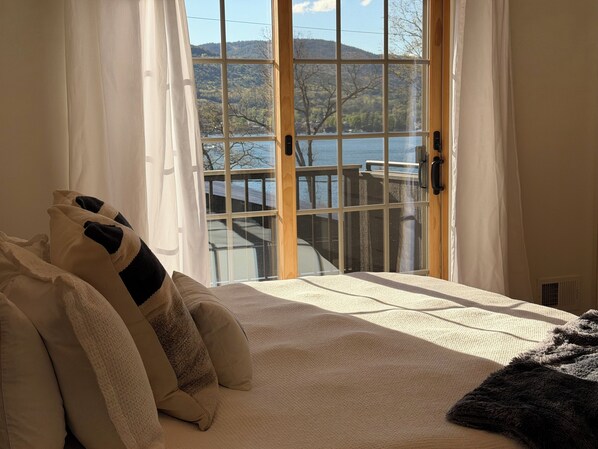 Un lit donnant sur un lac et des montagnes, avec une vue par la fenêtre.