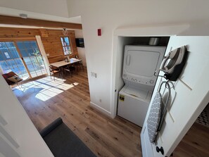 Une cuisine compacte dotée d’un lave-linge et d’un sèche-linge intégrés, d’un plancher en bois et d’un coin repas bénéficiant d’une lumière naturelle.