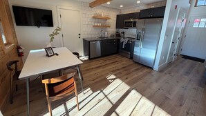 Een moderne keuken met een eethoek, houten vloeren en inbouwapparatuur.
