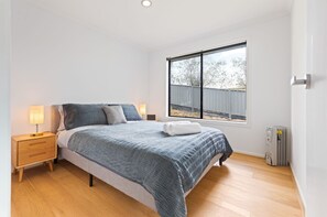 A bedroom with a bed, bedside lamps, a window, and a radiator. - Marlin Vista - Pet friendly, fenced yard (Eden)