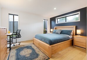 Une chambre à coucher comprenant un lit, un bureau, une chaise, une table de chevet et une fenêtre.