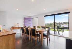 A modern dining area with a large table, chairs, and a view of the outdoors. - Marlin Vista - Pet friendly, fenced yard (Eden)