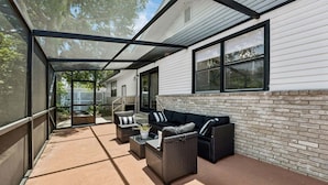 An outdoor patio with wicker furniture, a glass table, and a brick wall. - The Southwind|Pool|3-Min Drive to Beach|Sleeps 10 (St. Augustine)