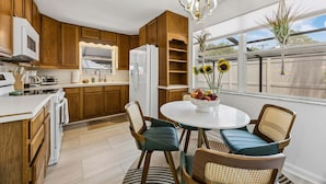A modern kitchen with wooden cabinets, a white refrigerator, a microwave, and a dining area with a round table and chairs. - The Southwind|Pool|3-Min Drive to Beach|Sleeps 10 (St. Augustine)