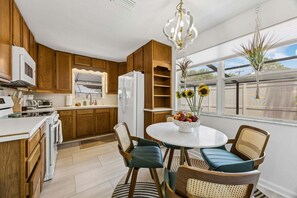 Una cucina moderna con mobili in legno, un frigorifero bianco, un forno a microonde e un'area pranzo con un tavolo rotondo e sedie.