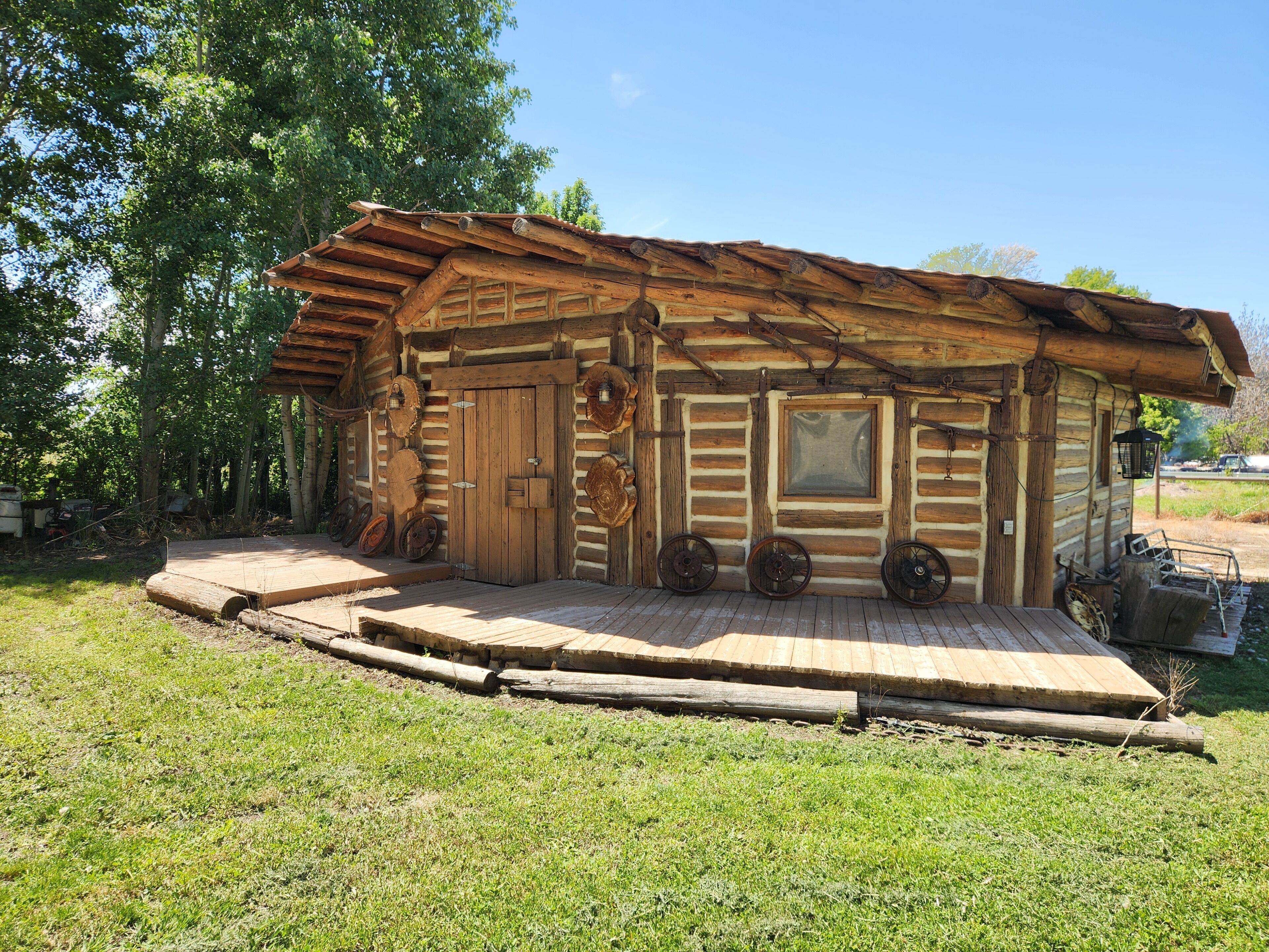 A rustic log cabin with a wooden door, a window, and a porch with wooden steps.. The Farm at Willard Bay - a unique home to stretch out and create memories!