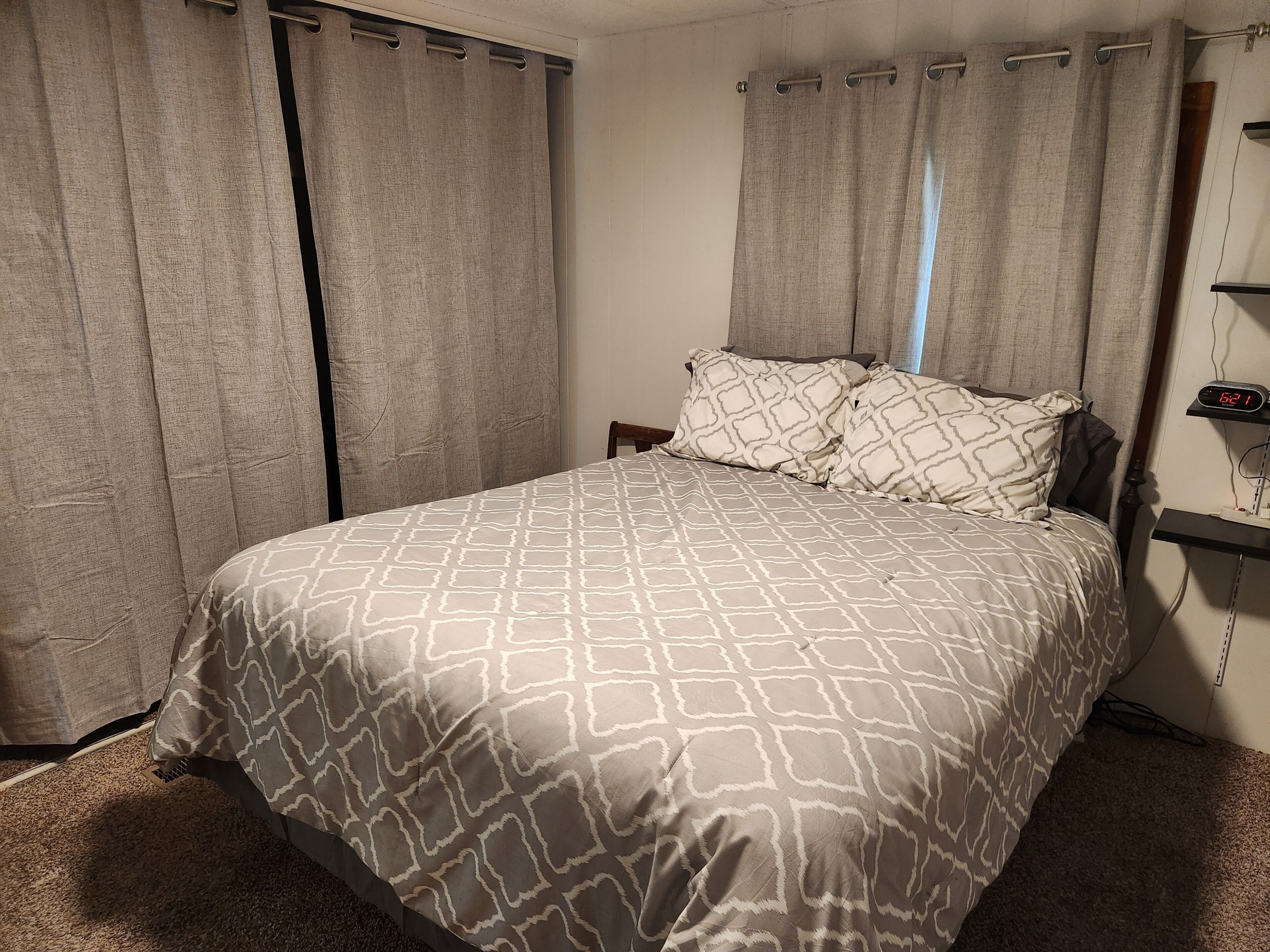 A bedroom with a bed, curtains, a nightstand, and a digital clock.. The Farm at Willard Bay - a unique home to stretch out and create memories!