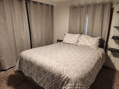 A bedroom with a bed, curtains, a nightstand, and a digital clock.. The Farm at Willard Bay - a unique home to stretch out and create memories!